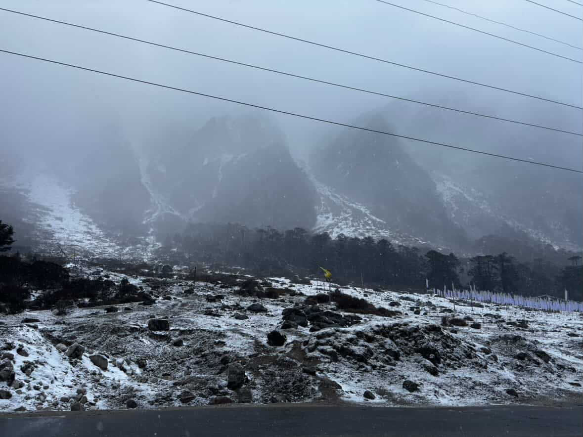 Mist drifting across snow-covered Himalayan peaks in Sikkim, seen from a high mountain viewpoint on a clear day